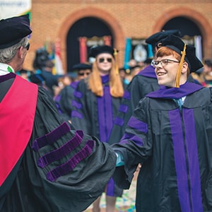 Regent Law graduate Jason Montgomery shakes hands with a faculty member during commencement ceremonies.