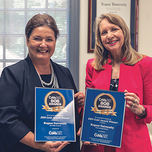 Dr. Doris Gomez and Martha Smith holding Coastal Virginia Magazine Best of Business awards for Regent University School of Business and Leadership
