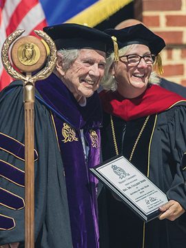 Dr. M.G. Pat Robertson, Regent University founder and chancellor, smiles during commencement as he presents an award on stage.