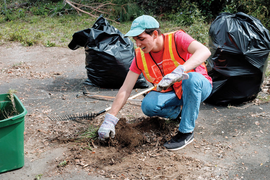 Regent University student volunteers clear debris and rake leaves in Panama City, Florida, as part of hurricane recovery efforts.