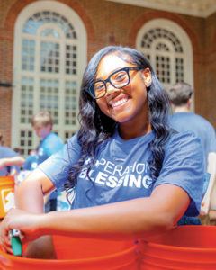 Regent University student smiles while helping assemble disaster-relief kits during the Operation Blessing outreach event on campus.
